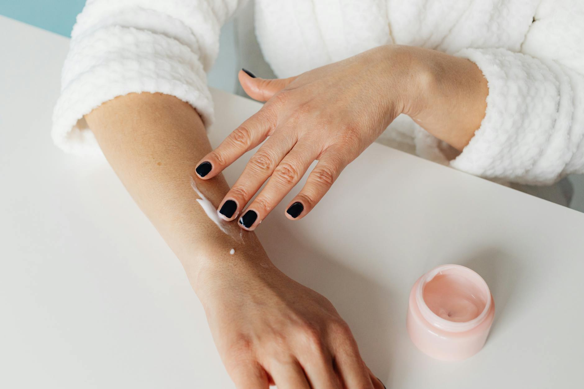 Close-up of hands applying skincare cream on arm, promoting beauty and wellness.